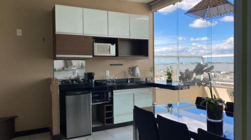 a kitchen with white cabinets and a large window at Manferrari Hotel in Contagem