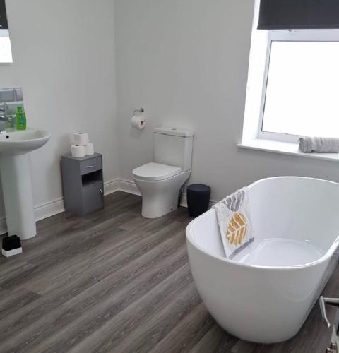 a bathroom with a white tub and a toilet at Englehurst Mews flat 2 in Buxton