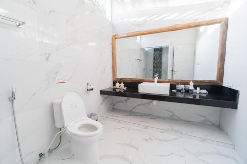 a white bathroom with a mirror and a toilet at Sea Shell Resort in Gili Trawangan