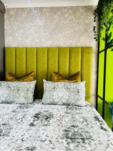a bedroom with a large bed with a green headboard at Modern studio apartments in Secunda