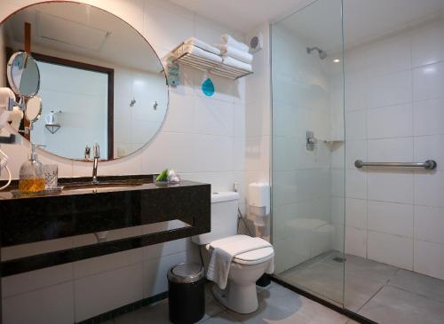 ein Badezimmer mit einem WC, einem Waschbecken und einem Spiegel in der Unterkunft Ritz Suítes-Maceió, Flat a Beira mar de temporada in Maceió