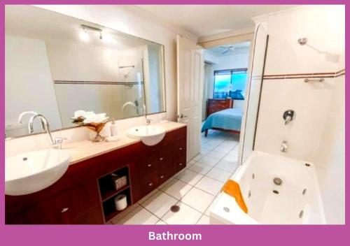 un bagno con due lavandini e un grande specchio di Magic Ocean Views On Melton a Townsville