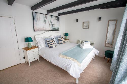 a bedroom with a large white bed with blue pillows at Whitby Boutique - Mast Cottage in Whitby
