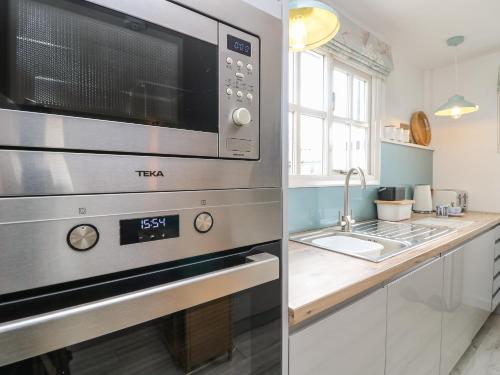 a kitchen with a stainless steel microwave and a sink at The Stables in Newport