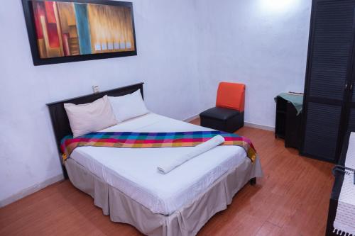 a bedroom with a bed and a orange chair at Hotel Makarios in Tuxtla Gutiérrez