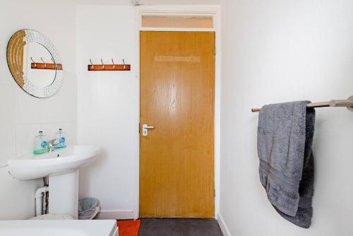 a bathroom with a sink and a wooden door at Ground Floor Apartment City Centre University Free Parking in Sheffield