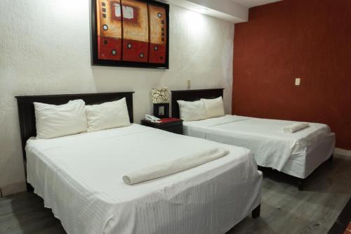 two beds in a hotel room with white sheets at Hotel Makarios in Tuxtla Gutiérrez