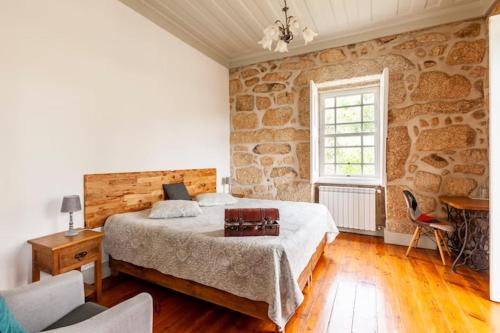 1 dormitorio con cama y pared de piedra en Casa do Cabeço en Caramulo