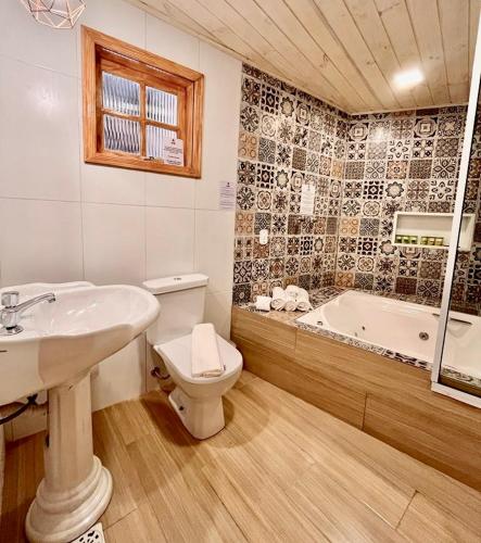 a bathroom with a sink and a toilet and a tub at Pousada Bliss House - Opções de suites com hidromassagem in Campos do Jordão