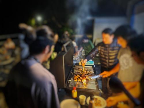 a group of people cooking food on a grill at A Promised Land BnB in Jiufen
