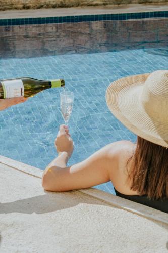 a woman in a hat holding a bottle and a wine glass at Ixchel Beach Hotel in Isla Mujeres