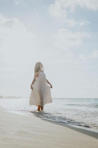 a woman in a dress walking on the beach at Ixchel Beach Hotel in Isla Mujeres