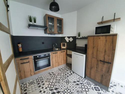 een keuken met houten kasten en een witte koelkast bij Maisonnette T1 avec jardin in Saint-Laurent-sur-Sèvre