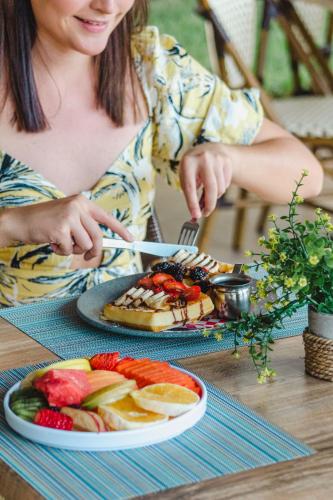 a woman sitting at a table with a plate of fruit at Ixchel Beach Hotel in Isla Mujeres