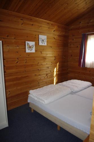 ein Schlafzimmer mit einem Bett in einer Holzhütte in der Unterkunft Chalets du Soleil in Mauroux