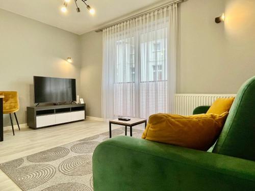 un soggiorno con un divano verde e una televisione di Apartamenty Planeta - Koszalin a Koszalin