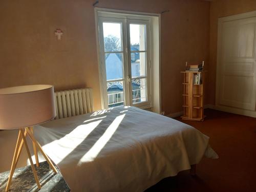 um quarto com uma cama e uma grande janela em Chambres à louer centre-ville em Le Mans
