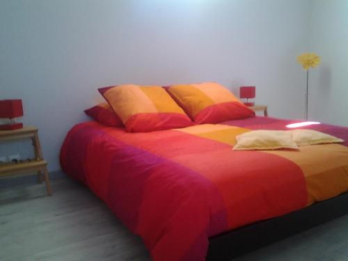 a bedroom with a bed with colorful sheets and pillows at Gîtes Les 3 Cigales in Vallon-Pont-dʼArc