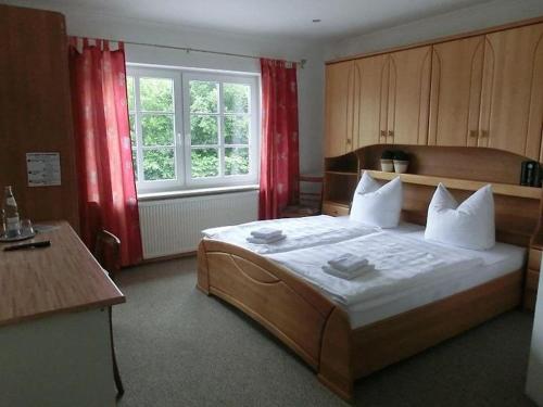 a bedroom with a large bed with red curtains at Landquartier in Schwesing