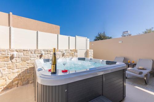 een hot tub op een patio met een fles champagne bij Konstantinos luxury suite in Koutsourás