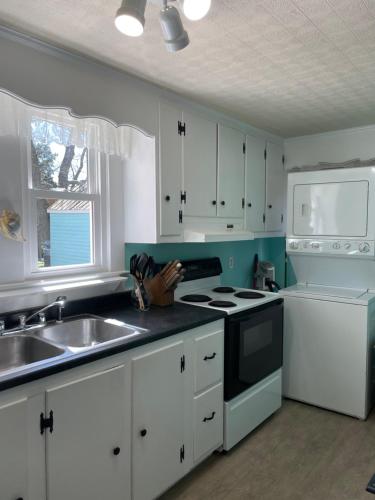 a kitchen with white cabinets and a sink and a stove at Seaside Retreat in Wachapreague