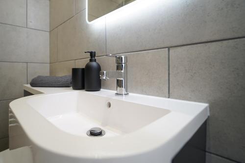 a white bathroom sink with a black soap dispenser on it at Beach Condos in Weston-super-Mare