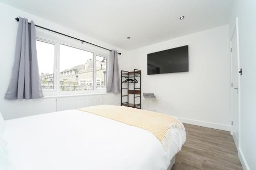 a white bedroom with a bed and a large window at Beach Condos in Weston-super-Mare