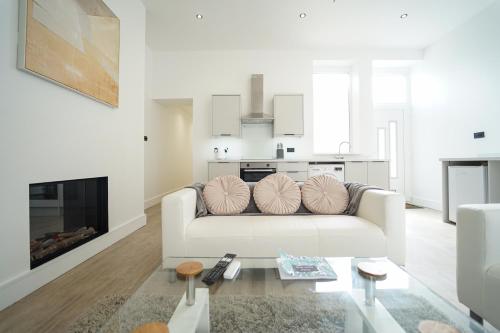 a white living room with a white couch and a fireplace at Beach Condos in Weston-super-Mare
