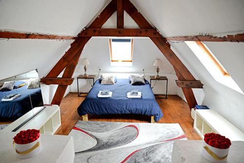 a attic bedroom with two beds and two tables at Villa Château Gontier in Château-Gontier