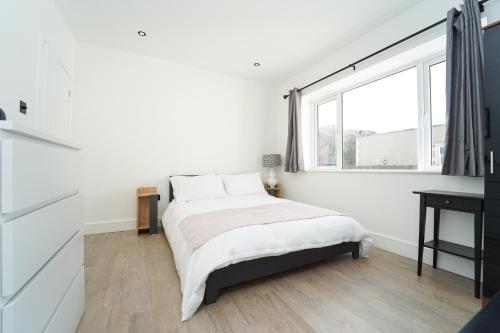 a white bedroom with a bed and a window at Beach Condos in Weston-super-Mare