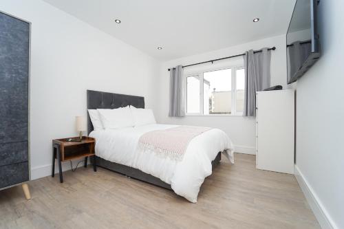 a white bedroom with a bed and a television at Beach Condos in Weston-super-Mare