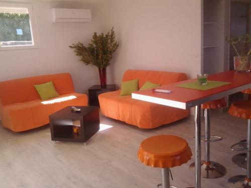 a living room with orange furniture and a table at Gîtes Les 3 Cigales in Vallon-Pont-dʼArc