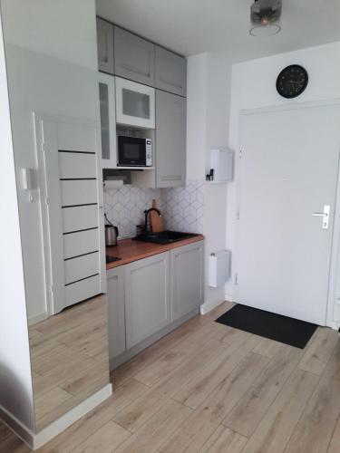 a kitchen with white cabinets and a wooden floor at George Studio przy Stadionie Narodowym in Warsaw