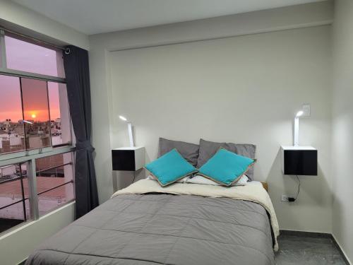um quarto com uma cama com duas almofadas azuis em Apartamentos "APPART D'ELIETTE" em Trujillo
