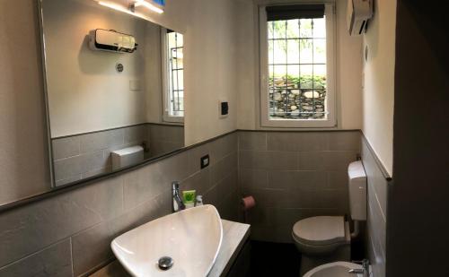 bagno con lavandino, servizi igienici e specchio di Casa Ninou a Domaso