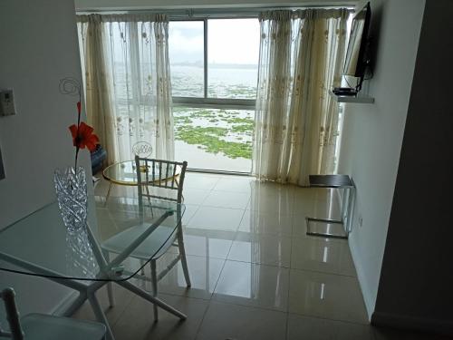 a dining room with a glass table and a window at Ecusuites Riverfront One Vista al Río Jacuzzi Hidro in Guayaquil