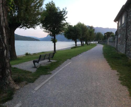 a bench sitting on the side of a road next to a lake at Casa Ninou in Domaso