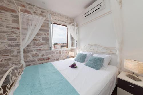 um quarto com uma cama branca e uma parede de tijolos em Imperium Central Apartments Zadar em Zadar