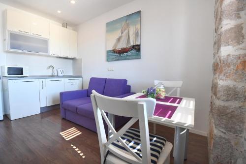 uma cozinha e uma sala de estar com uma mesa e um sofá roxo em Imperium Central Apartments Zadar em Zadar