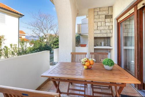 una mesa de madera con fruta en el balcón en Apartments Villa Bernarda, en Šilo