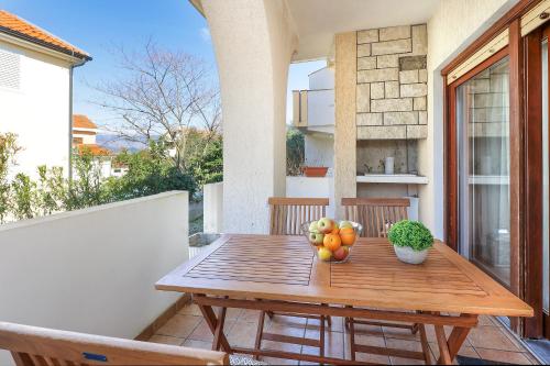 a wooden table with fruit on a balcony at Apartments Villa Bernarda in Šilo