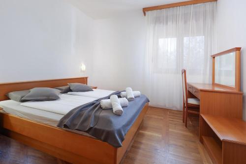 a bedroom with a bed and a desk and a window at Apartments Villa Bernarda in Šilo