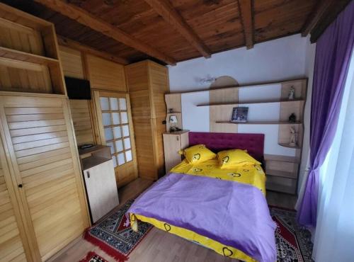 a bedroom with a yellow bed in a wooden room at Casa Roza in Breaza de Sus
