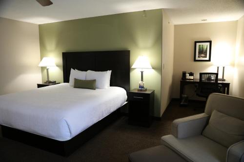 a hotel room with a bed and a chair at Baymont by Wyndham Rockford in Rockford