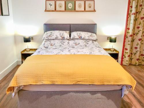 um quarto com uma cama com um cobertor amarelo em The Goat Shed em Hadlow