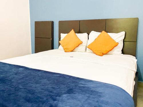 a large bed with two orange pillows on it at Hotel Amigo Suites in Mexico City