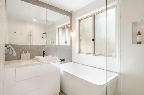 a white bathroom with a tub and a sink at Lennox Beach Oasis 3 Bedrooms in town in Lennox Head