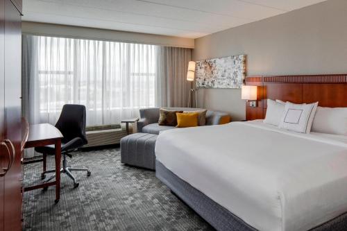 a hotel room with a bed and a desk and a couch at Courtyard by Marriott Boston Logan Airport in Boston