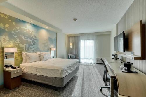 サジントンにあるCourtyard by Marriott Southingtonのベッドとデスクが備わるホテルルームです。