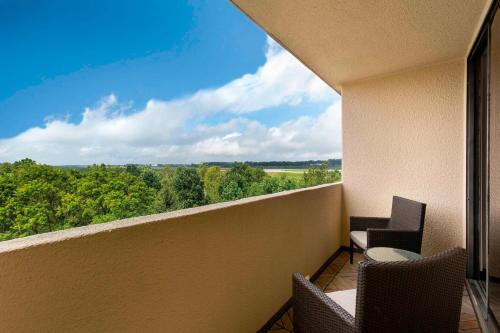 a balcony with two chairs and a view of trees at Greensboro-High Point Marriott Airport in Greensboro